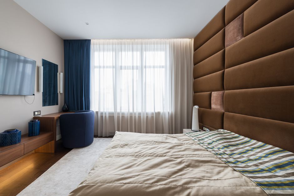 Interior of stylish bedroom with comfortable large bed in contemporary apartment in daytime